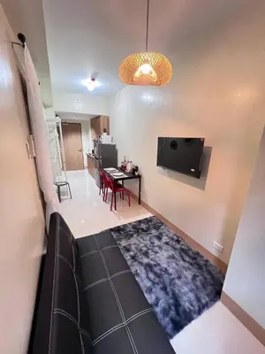 a living room with a couch and a tv and a table at Unistay SHORE 3 Tower 2 Pool View Cozy Suite in Manila