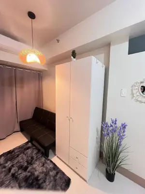 a living room with a couch and a cabinet at Unistay SHORE 3 Pool view w Balcony near MOA in Manila