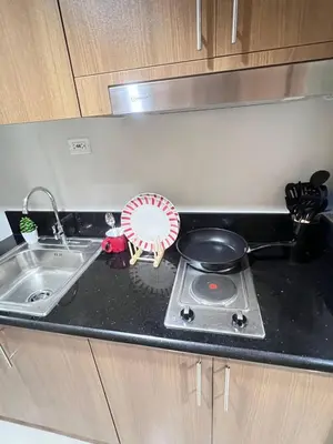 a kitchen counter with a stove and a sink at Unistay SHORE 3 Tower 2 10th Floor w Balcony Pool View in Manila