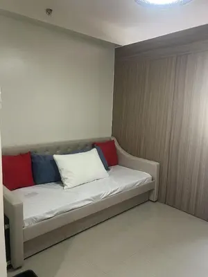 a couch with three pillows on it in a room at Shore 2 Residences Executive Suite by JMS in Manila