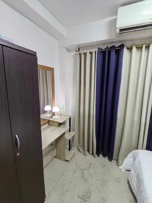 a bedroom with a bed and a desk and curtains at Shore Residences in Manila