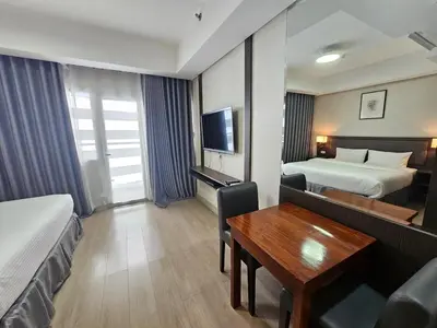 a hotel room with two beds and a desk at The Residences at BCCT by Stays PH Cozy retreat with hotel-style comforts and convenience, best location in BGC in Manila