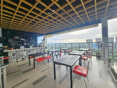 a restaurant with tables and chairs and a balcony at The Residences at BCCT by Stays PH Cozy retreat with hotel-style comforts and convenience, best location in BGC in Manila