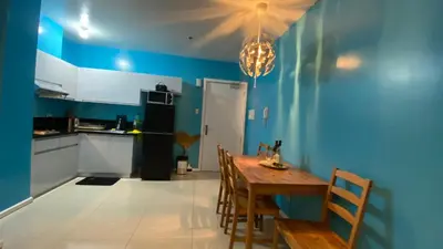 a kitchen with blue walls and a wooden table and chairs at The Radiance Manila in Manila