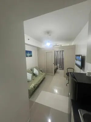 a living room with a bed and a television at Sojourn at Sea Residences MOA in Manila