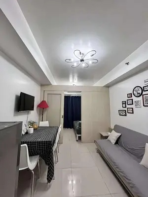 a living room with a dining table and a ceiling fan at Sojourn at Sea Residences MOA in Manila