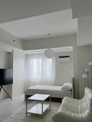 a bedroom with a bed and a couch and a table at Cloud Space Studio near Eastwood in Manila