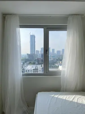 a bedroom with a bed and a window with white curtains at Cloud Space Studio near Eastwood in Manila