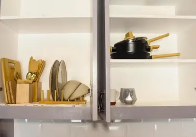 a shelf with plates and utensils in a kitchen at The Brass Burrow, Bel Air Soho Suites in Manila