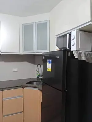 a kitchen with a black refrigerator and a sink at Romeotwopalmtreevilla in Manila