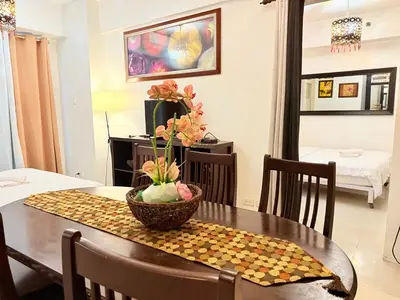 a dining room table with a bowl of flowers on it at The Nook Stays at Sea Residences in Manila