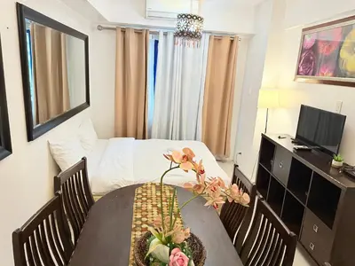 a room with a table with chairs and a bed at The Nook Stays at Sea Residences in Manila