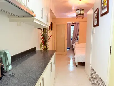 a kitchen with a counter and a bed in a room at The Nook Stays at Sea Residences in Manila