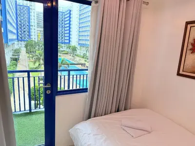 a bedroom with a bed and a window with a view at The Nook Stays at Sea Residences in Manila