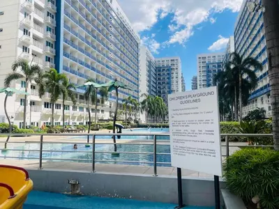 a sign in front of a swimming pool with buildings at The Nook Stays at Sea Residences in Manila