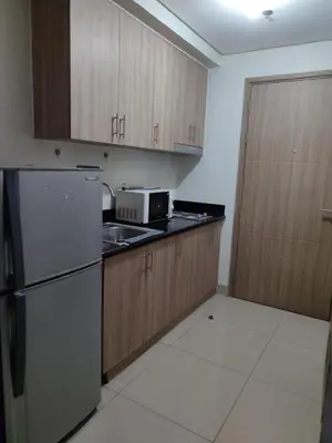 a kitchen with wooden cabinets and a refrigerator at Staycation at Shore 2 Residences Tower 1 Near Moa, PICC, STARCITY, WORLD TRADE, SMX, MOA ARENA & NAIA 123 in Manila