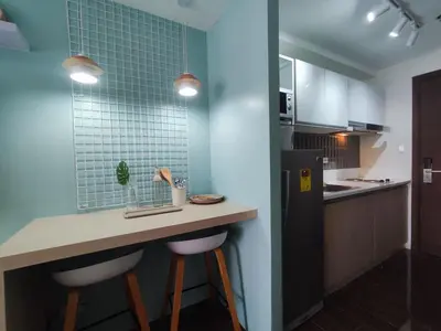 a kitchen with a counter with stools and a refrigerator at Newly Designed 1BR Top of Makati in Manila