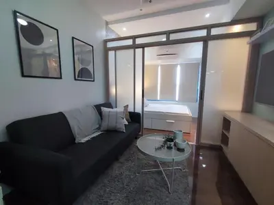 a living room with a black couch and a table at Newly Designed 1BR Top of Makati in Manila