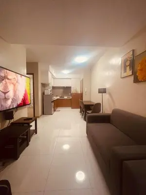 a living room with a couch and a flat screen tv at Cozy Studio Unit located at serene area in Manila