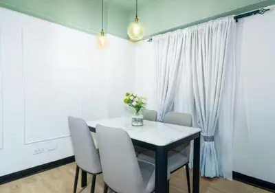 a dining room with a white table and white chairs at Villa Verde, Tivoli Garden Residences in Manila