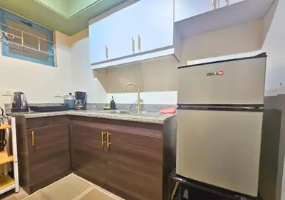 a kitchen with a refrigerator and wooden cabinets at Villa Verde, Tivoli Garden Residences in Manila