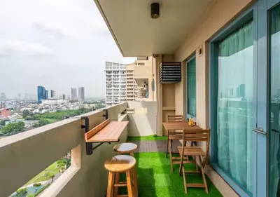 a balcony with wooden tables and chairs and a view at Villa Verde, Tivoli Garden Residences in Manila