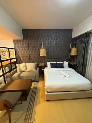 a hotel room with a bed and a couch at Cozy studio unit in Avant BG in Manila