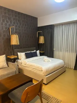a bedroom with a king sized bed and a chair at Cozy studio unit in Avant BG in Manila