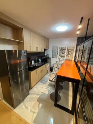 a kitchen with a wooden table and a stainless steel refrigerator at Cozy studio unit in Avant BG in Manila