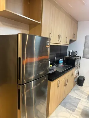 a kitchen with a stainless steel refrigerator and wooden cabinets at Cozy studio unit in Avant BG in Manila