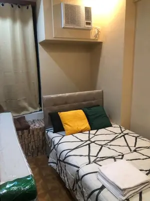 a small bedroom with a bed and a air conditioner at South Sanctuary in Manila