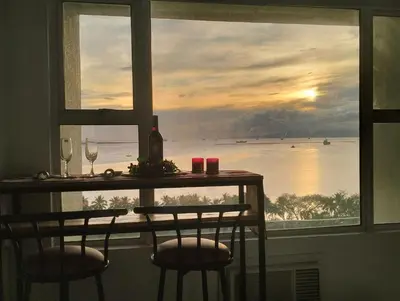 a table with two glasses and a view of the ocean at Chic Haven in Manila