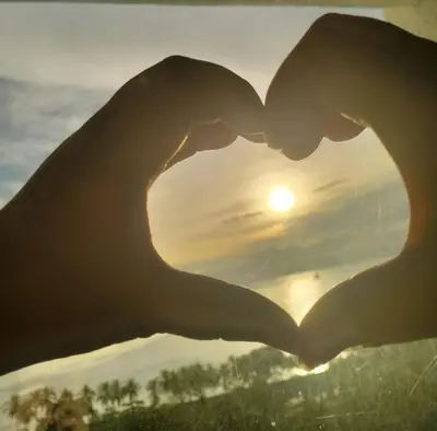 a pair of hands forming a heart with the sunset in the background at Chic Haven in Manila