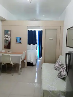a hotel room with a bed and a table and a bed and a bedroom at Sea Residence Finest By Douie in Manila