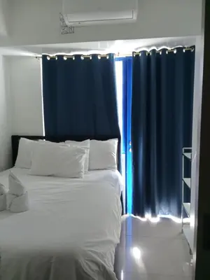 a bedroom with a bed with a blue curtain at Sea Residence Finest By Douie in Manila