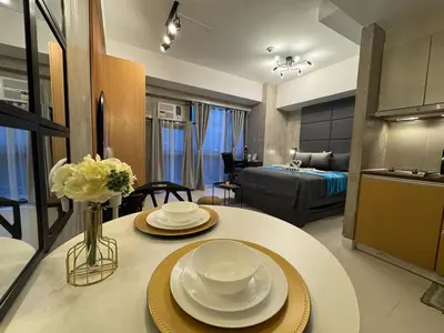 a kitchen and a living room with a table with plates at Industrial Chic Studio in McKinley Hill Walk to Venice Mall in Manila