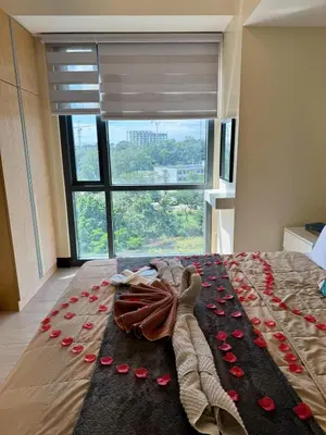 a bed with red rose petals on it with a window at Cozy Viceroy 1BR, Walk to Venice Mall in Manila