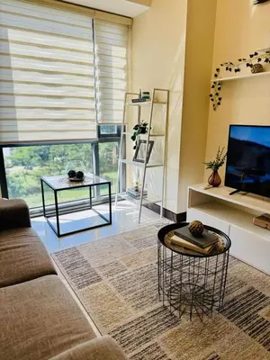 a living room with a couch and a tv at Cozy Viceroy 1BR, Walk to Venice Mall in Manila