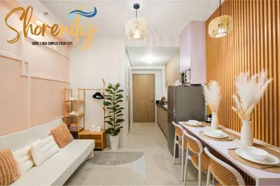 a living room with a table and a refrigerator at Shorenity MOA Staycation in Manila
