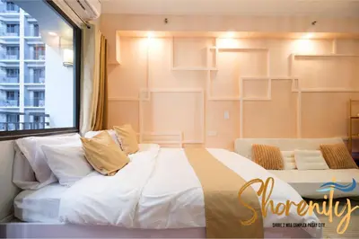 a bedroom with a large bed and a large window at Shorenity MOA Staycation in Manila