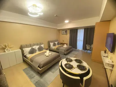 a living room with two beds and a tv at The Serene Casa - EMANUELE TOWER in Manila