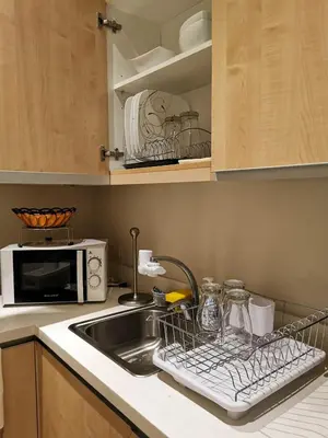 a kitchen sink with a dish drying rack next to a microwave at Spacious 1BR APT near Nightlife and Business Center in Makati in Manila