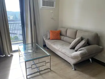a living room with a couch and a glass table at 2mins to Okada near Airport & MOA with Balcony-8E in Manila
