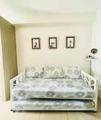 a white bed in a white room with pictures on the wall at Shore 1 Condo near MOA - PLS send valid IDs of all guests after booking for guest authorization form purposes in Manila