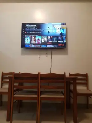 a flat screen tv hanging on a wall with two benches at Shore 2 Residences MOA Pasay Naia in Manila