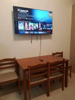 a table and a bench with a television on the wall at Shore 2 Residences MOA Pasay Naia in Manila
