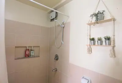 a bathroom with a shower with plants on the wall at Brixton Place in Manila