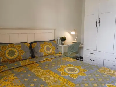 a bed with a yellow and blue comforter and a desk at Brixton Place in Manila