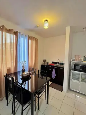 a dining room with a table and chairs and a kitchen at Luna staycation Cozy Condo near Enchanted Kingdom in Santa Rosa