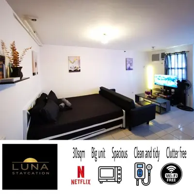 a living room with a black couch and a tv at Luna staycation Cozy Condo near Enchanted Kingdom in Santa Rosa